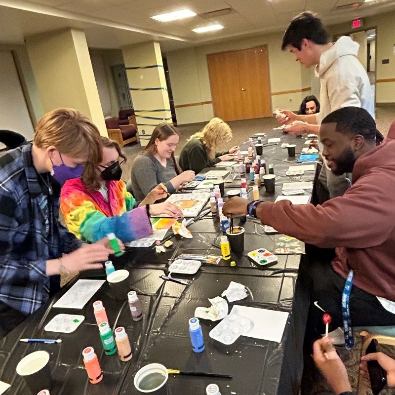 Students sitting around a large table painting 