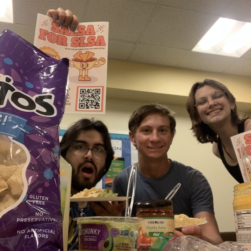 Students sitting with chips and salsa holding up a poster that reads "Salsa for SLSA"