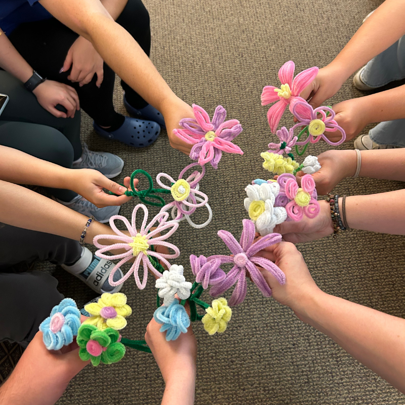 Students holding homemade pipe cleaner flowers