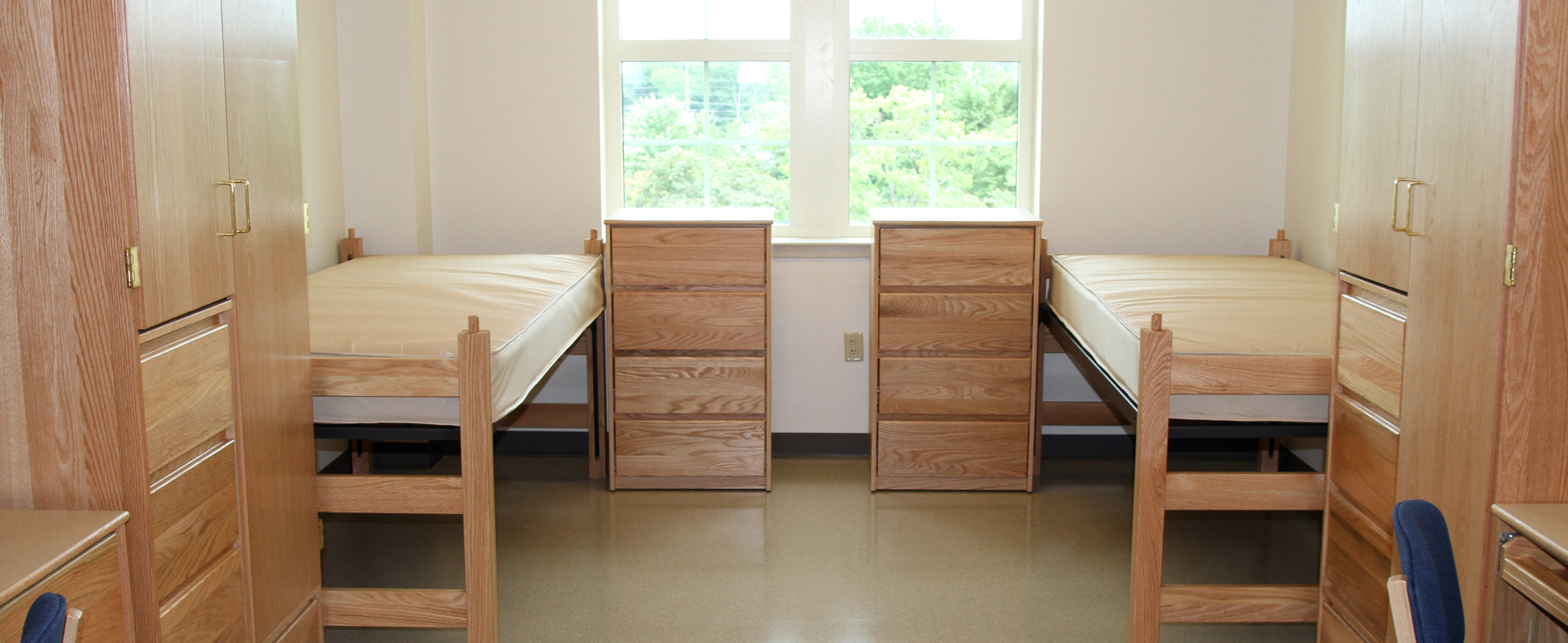 Sunlit Gilbert room interior with two beds, dressers, desks and wardrobes