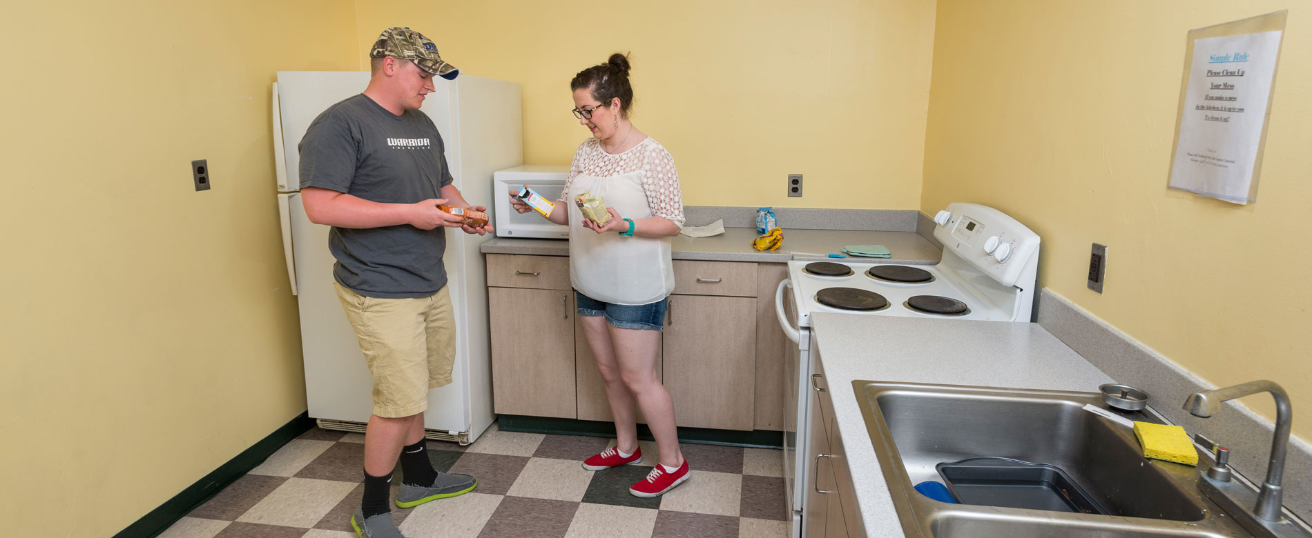 Students stand and talk in a common kitchen area