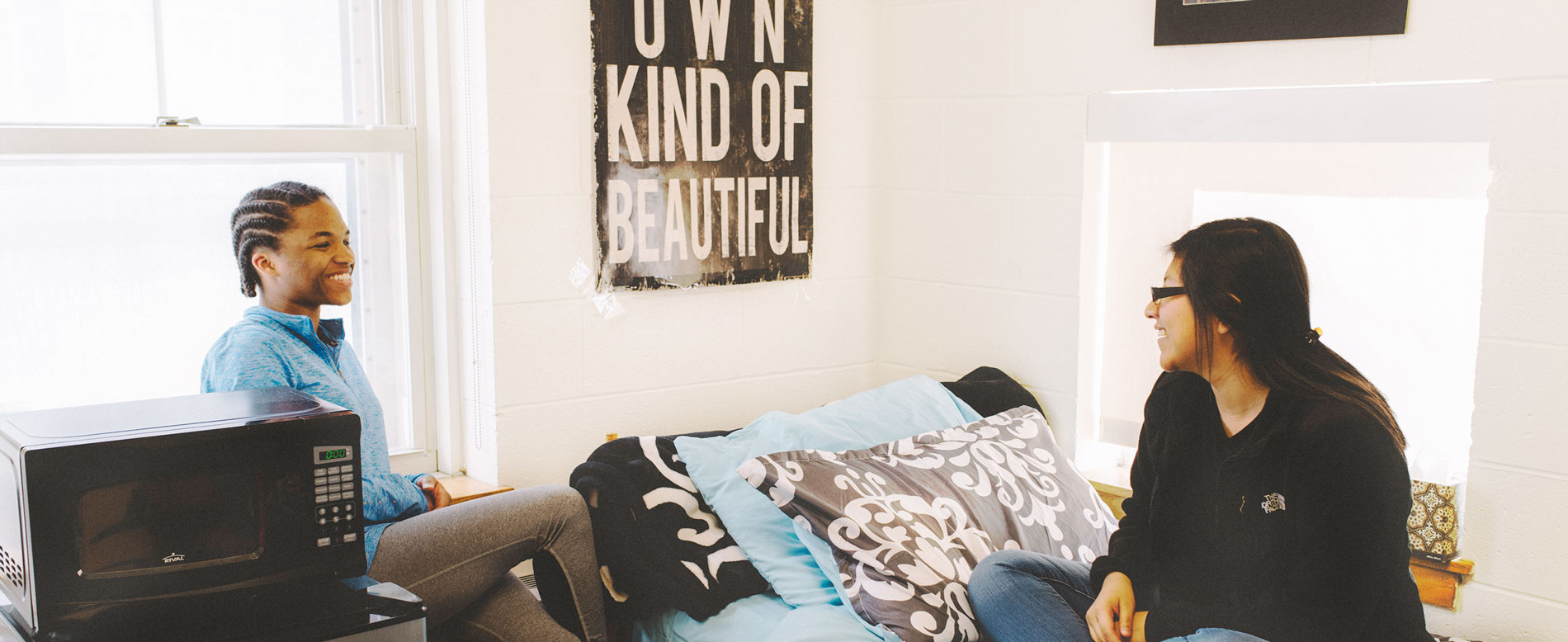 Two students sit on beds and chat in a Ray Street room