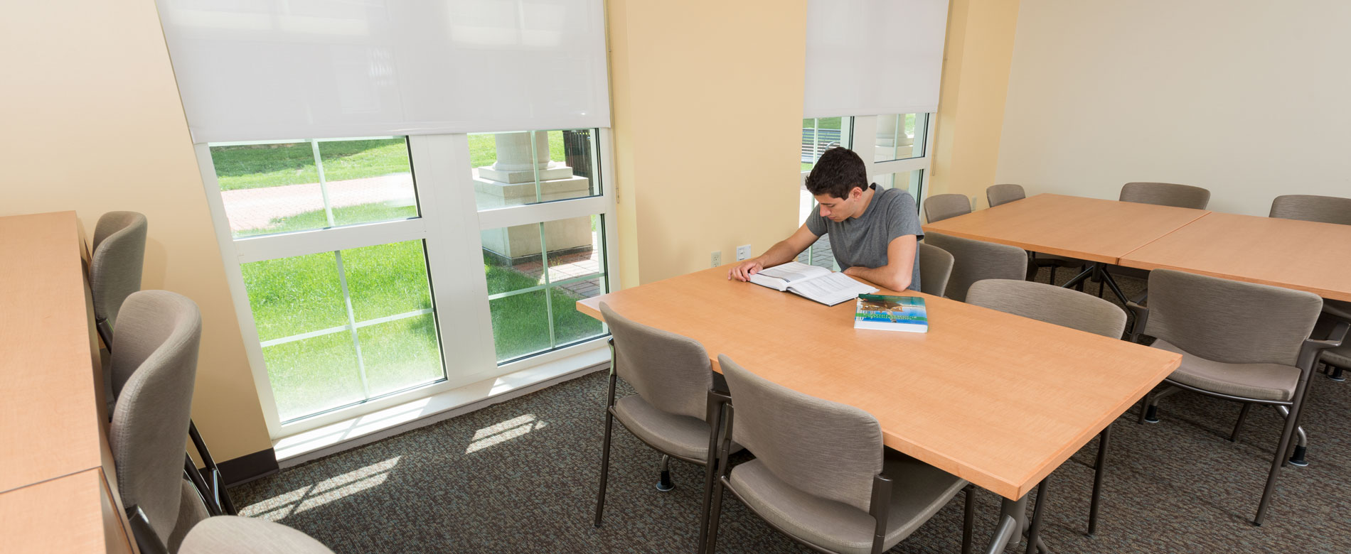 Student studying in common area with tables and chairs