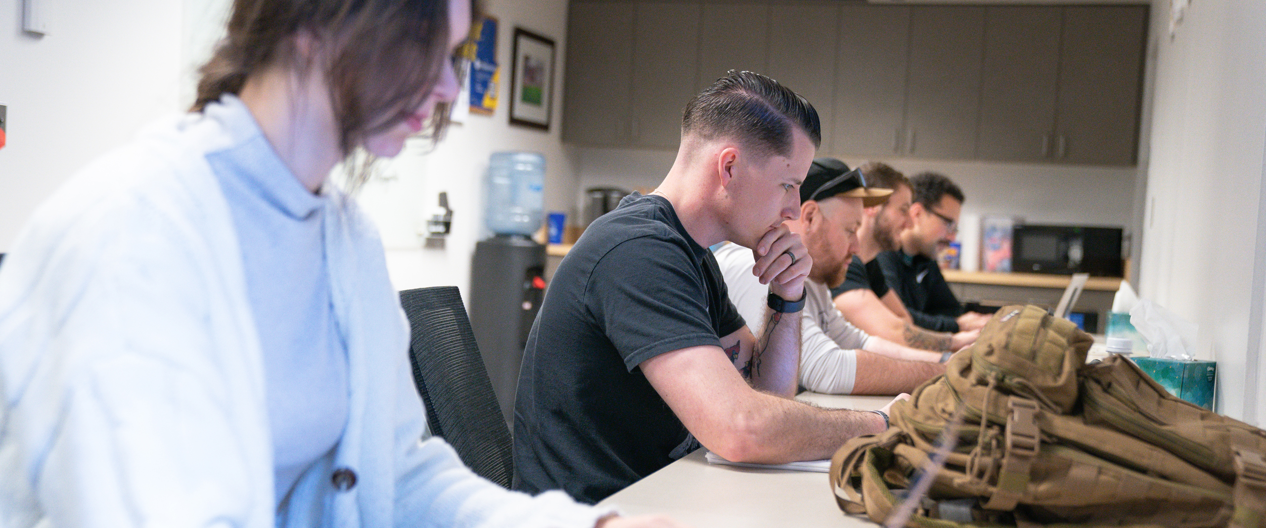 several students work on laptops at a counter in the Military Lounge