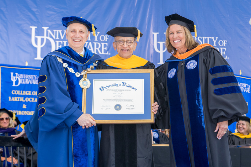 Rakesh Jain, a UD alumnus and now director of the Edwin L. Steele Laboratory for Tumor Biology at Massachusetts General Hospital, is congratulated on his new honorary doctor of science degree by UD President Dennis Assanis and Board Chair Terri L. Kelly.