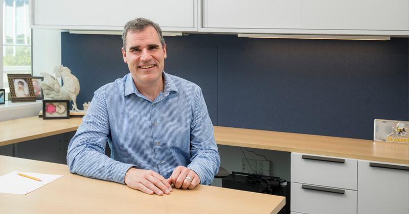 Joseph Fox, professor of chemistry and biochemistry sitting behind a desk