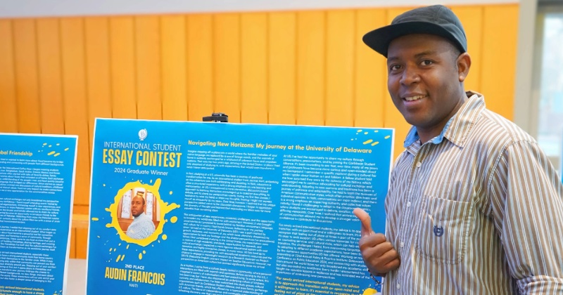 Pictured is Audin Francois, second place winner in the graduate student category, with a poster of his essay on display in Trabant University Center during International Education Week.