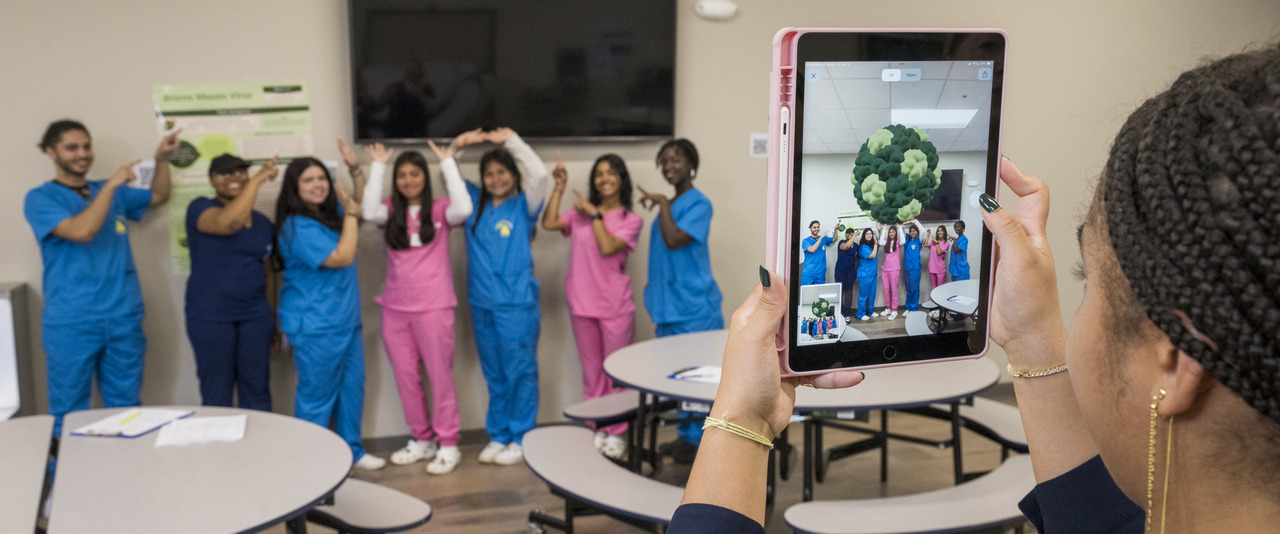 Students from Las Américas ASPIRA Academy High School pose with an augmented reality model of a Brome mosaic virus, part of the VirusGo teaching platform developed by University of Delaware chemistry professors Jodi Hadden-Perilla and Lauren Genova and undergraduates Riley McKeon and Ava West. VirusGo combines AR and a role-playing game to teach students about viruses.