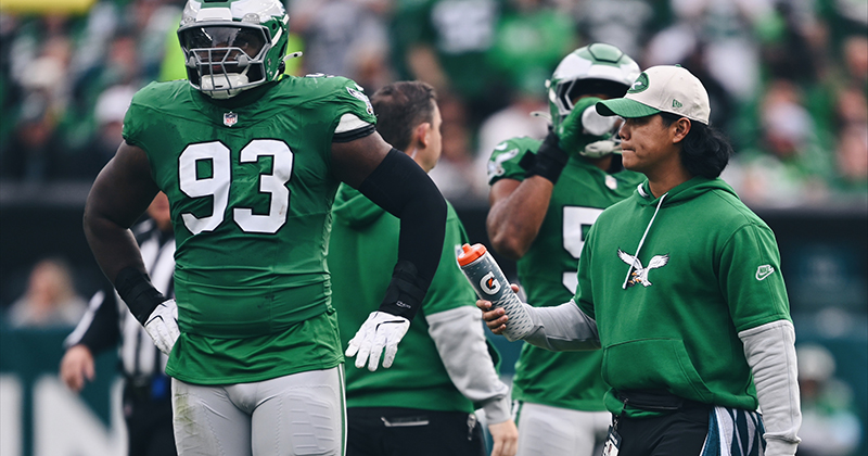 Marco Diaz (right), a seasonal athletic trainer in his first year with the Eagles, ensures players like defensive tackle Milton Williams (left) stay hydrated during a home game against the Dallas Cowboys. (Photo courtesy of Philadelphia Eagles Video Staff.)