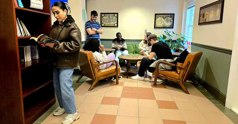 Students in a room looking at books and sitting at a table