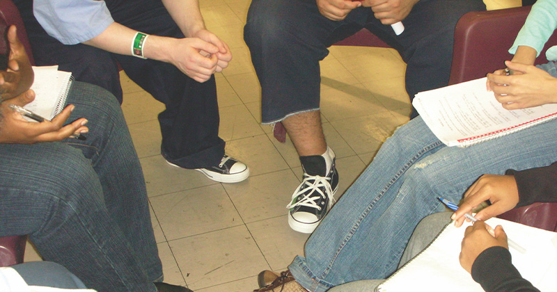 picture of people sitting in a circle with notebooks