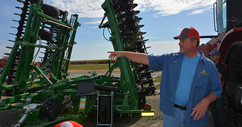 Mark Isaacs by an agricultural machine.