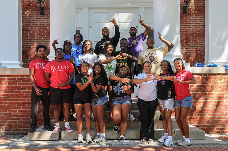 Sorority and fraternity members making greek letters with their hands