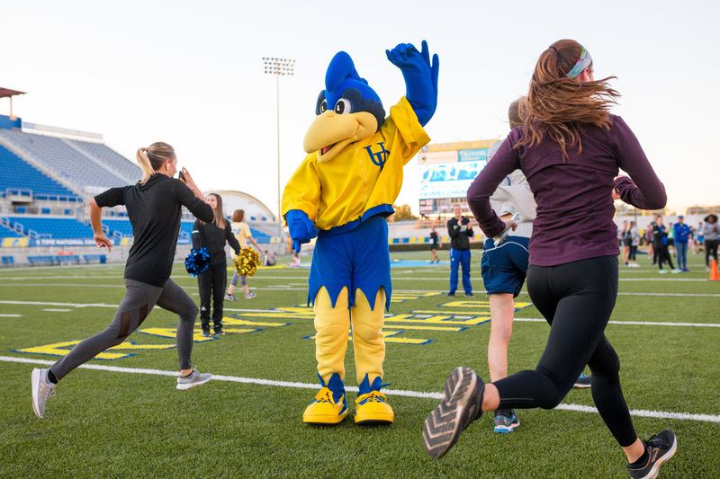 Homecoming 5k at Delaware Stadium YoUDee waves at students as the sprint across the football field