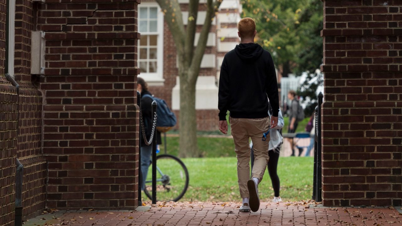Fall Campus - 10.30.19 student walking under arches on the Green