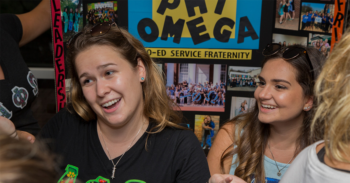 Members of Alpha Phi Omega speak with students during a tabling event