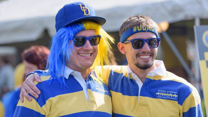 Two students wearing blue and gold with UD accessories