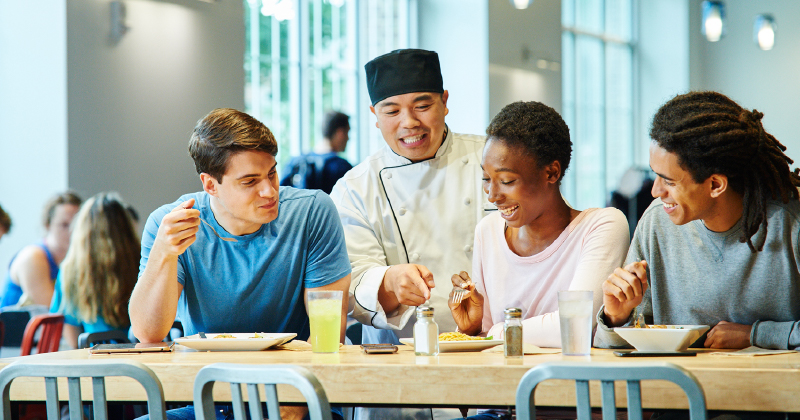 Aramark chef talking to three UD students