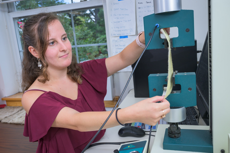 Michelle Yatvitskiy inserts the fabric sample into a machine to test its tensile strength. The machine pulls the fabric in different directions until it rips. 