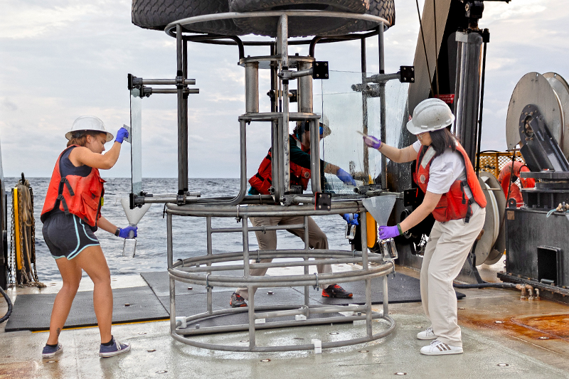 University of Delaware associate professor Andrew Wozniak co-led a research cruise aboard UD’s Research Vessel Hugh R. Sharp to study the sea surface microlayer in the North Atlantic Ocean. Pictured here are researchers working with a Rosette sampler, a device used for water sampling in deep water, outfitted with pieces of glass. These glass panels collect the ocean material by being dipped into the water and then having the researchers take a squeegee to scrape the water that stuck to the plate into a bottle. 