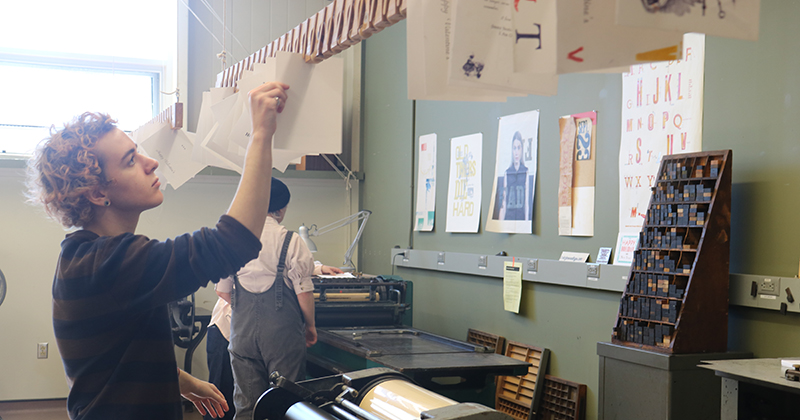 Rowan Dominick, who worked at Raven Press helping sort tiles, hangs newly printed cards to dry. Rowan Dominick, who worked at Raven Press helping sort tiles, hangs newly printed cards to dry.