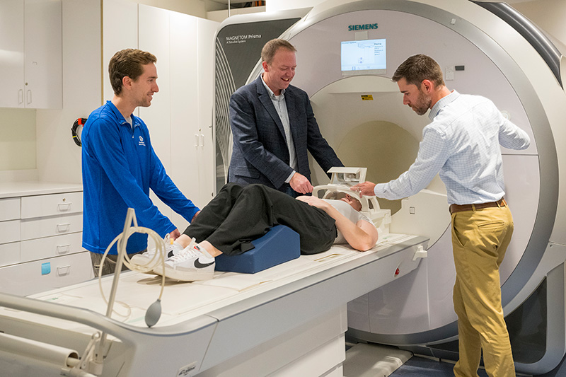 The DCF grant will fund the purchase of a new state-of-the-art MRI machine on STAR Campus to support DECCAR executive committee member Curtis Johnson’s (inner left) work with DECCAR director Christopher Martens (right) to use magnetic resonance elastography to explore links between brain stiffness and cognitive impairment. The DCF grant will fund the purchase of a new state-of-the-art MRI machine on STAR Campus to support DECCAR executive committee member Curtis Johnson’s (inner left) work with DECCAR director Christopher Martens (right) to use magnetic resonance elastography to explore links between brain stiffness and cognitive impairment.